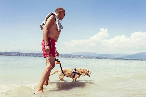 Homem maduro relaxante com seu cão na água doce — Fotografia de Stock