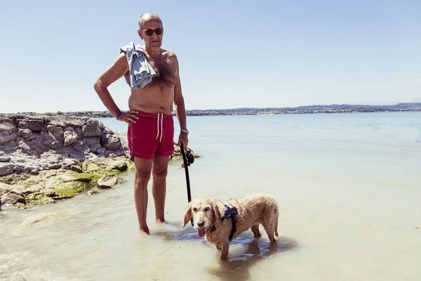 Mature homme relaxant avec son chien dans l'eau douce — Photo