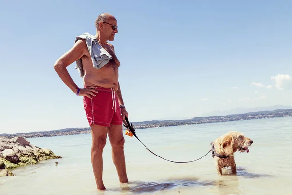 Mature homme relaxant avec son chien dans l'eau douce — Photo