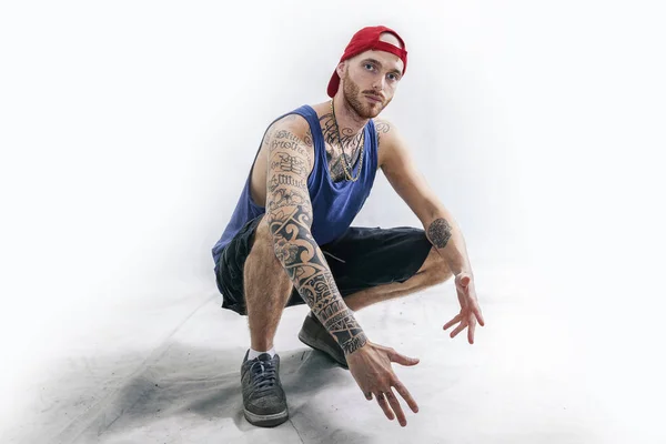 Sentado tatuado rap cantante posando en estudio — Foto de Stock