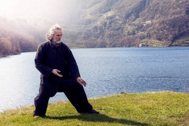 mature man practicing Tai Chi discipline outdoors clipart