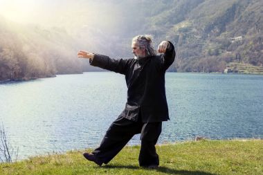 mature man practicing Tai Chi discipline outdoors clipart