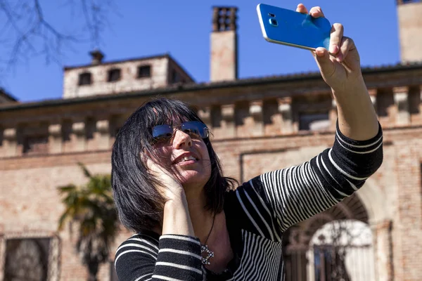 Ładna kobieta biorąc selfie, naprzeciwko średniowiecznego zamku — Zdjęcie stockowe
