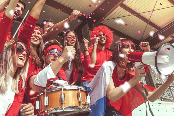 Група фанатів, одягнених у червоний колір, дивиться спортивну подію — стокове фото