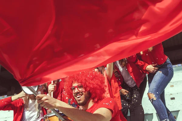 Gruppo di fan vestiti di colore rosso guardando un evento sportivo — Foto Stock