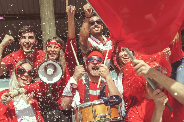Grupa fanów ubrany w czerwony kolor oglądania zawodów sportowych — Zdjęcie stockowe