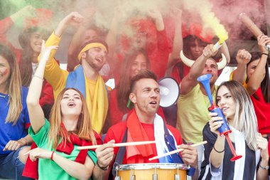 bir spor olayı izlerken kırmızı renkte giyinmiş hayranları grup