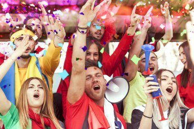 bir spor olayı izlerken kırmızı renkte giyinmiş hayranları grup