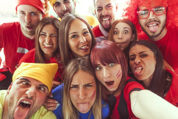 Gruppe rot gekleideter Fans macht ein Selfie auf der Tribüne — Stockfoto