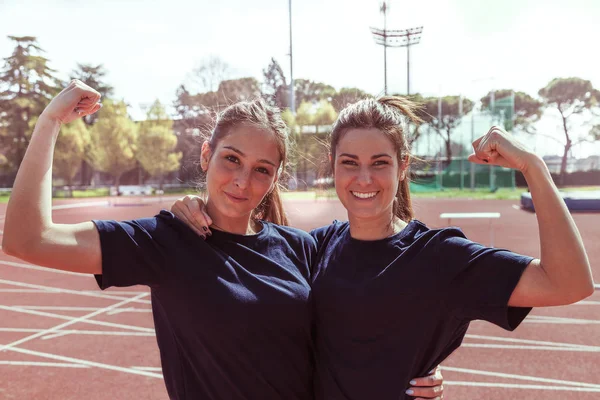 Dwie młode piękne uśmiechający się sportowców Wyświetlono mięśni — Zdjęcie stockowe