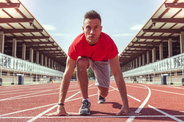 Jovem atleta determinado a iniciar blocos prontos para a corrida — Fotografia de Stock