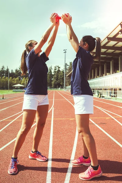 Deux jeunes et belles athlètes féminines haltère levant — Photo