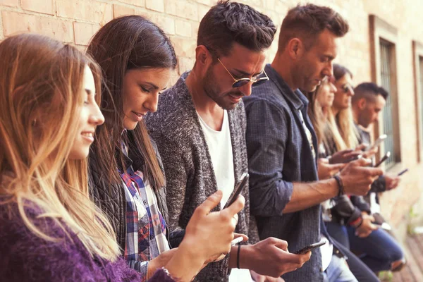 Duża grupa przyjaciół za pomocą smart telefonu ścianę czerwony — Zdjęcie stockowe