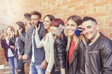 kırmızı bir duvara akıllı telefon kullanan arkadaşlar büyük bir grup