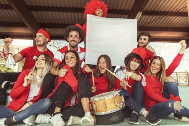 bir spor olayı izlerken kırmızı renkte giyinmiş hayranları genç grup