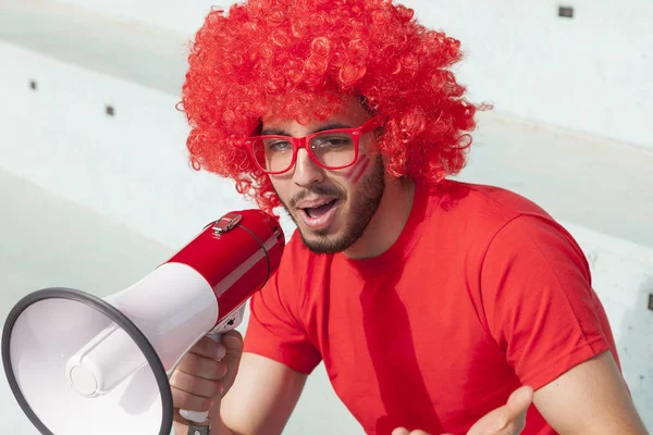 Mlody kibic fan ubrany w kolorze czerwonym, krzycząc w megapho — Zdjęcie stockowe