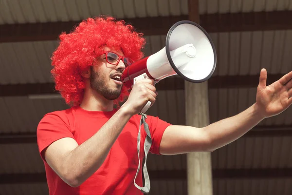 Νεαρός υποστηρικτής ανεμιστήρα ντυμένος με κόκκινο χρώμα, φωνάζοντας τα megapho — Φωτογραφία Αρχείου