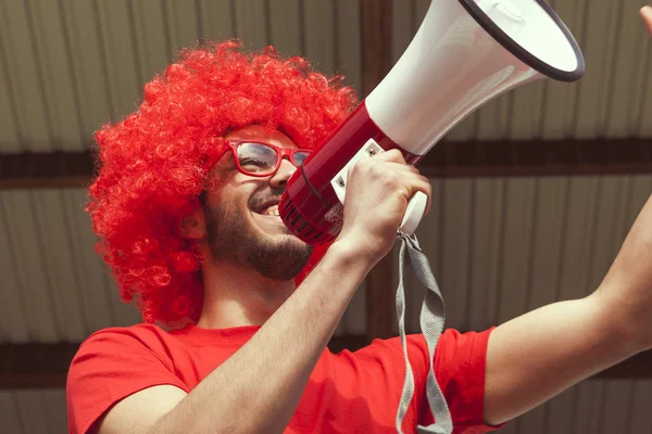 Jonge aanhanger sexy gekleed in rode kleur schreeuwen in de megapho — Stockfoto