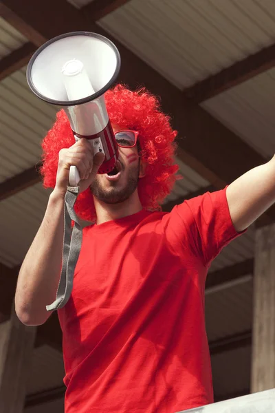 Mlody kibic fan ubrany w kolorze czerwonym, krzycząc w megapho — Zdjęcie stockowe