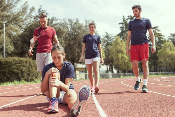 Mladý sportovec zraněné koleno na trati — Stock fotografie