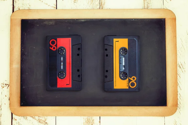 Pair of vintage audio cassettes over a black chalkboard — Stock Photo, Image