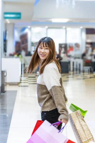 Docela šťastný mladý číňan žena s barevné nákupní tašky — Stock fotografie