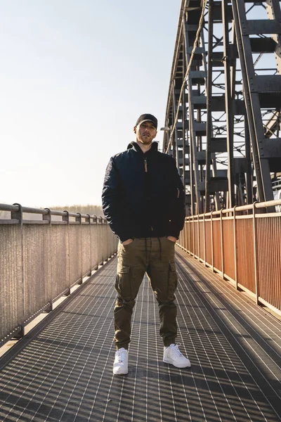 Retrato de joven rapero posando bajo un puente de metal — Foto de Stock