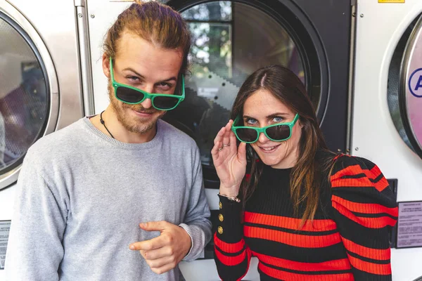 Молодая любящая пара в зеленых солнцезащитных очках в общественной прачечной — стоковое фото