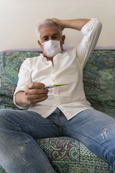 Homem Maduro Com Máscara Medindo Sua Febre Com Termômetro Digital — Fotografia de Stock
