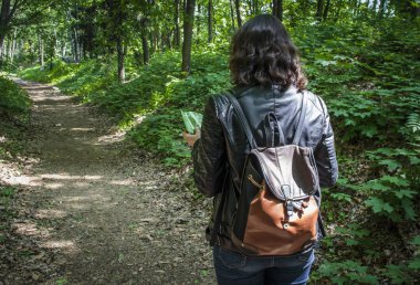 Ormanın içinde harita bakarak bir sırt çantası ile kız