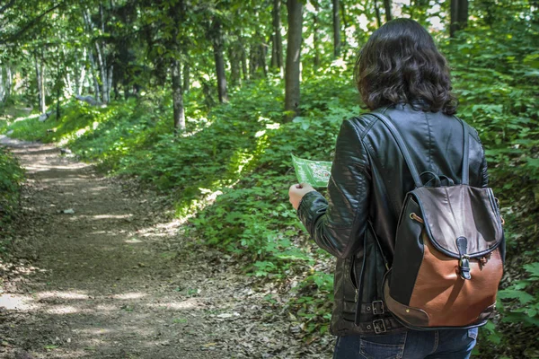 Ormanın içinde harita bakarak bir sırt çantası ile kız