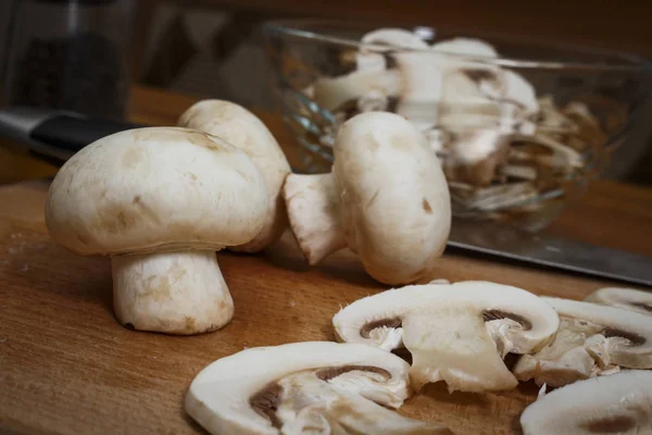 Champignons in Scheiben geschnitten in der Küche auf einem Schneidebrett — Stockfoto