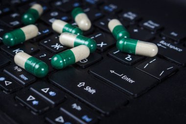 Laptop klavye üzerinde yeşil kapsül yığını