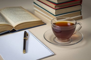 Çay, kitap ve beyaz masa üstünde defter