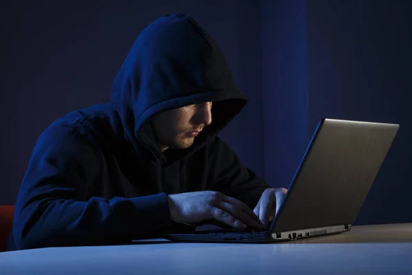 Genç bir adam bir başlıklı arkasında bir dizüstü bilgisayar