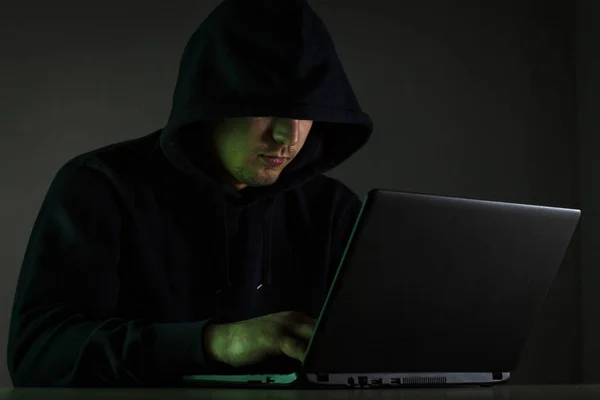 Genç bir adam bir başlıklı arkasında bir dizüstü bilgisayar