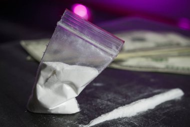 Bir avuç dolar yanında beyaz toz plastik torba