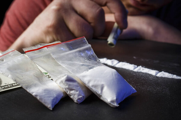 Drug addict man using narcotics, sniffing cocaine lines white po
