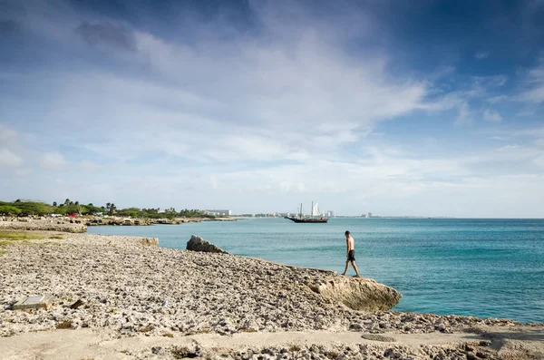 Uomo che cammina con una barca a vela ancorata come sfondo — Foto Stock