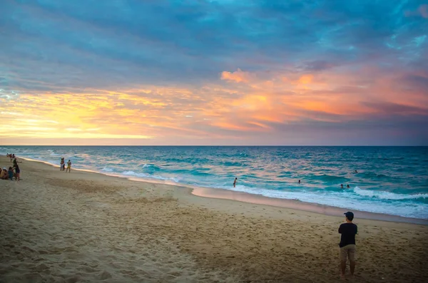 Západ slunce na pláži s turisty těší — Stock fotografie