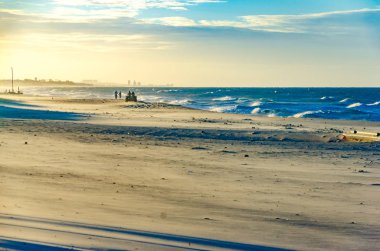 Adamcağız dört bir yanındaki insanlarla batımında sahilde
