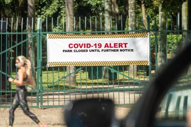 Covid-19 alarmı. Park ikinci bir emre kadar kapalı. Park kapandığı için sokakta maskeli bir kadın koşuyor..