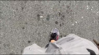 Sokakta şort ve spor ayakkabı giyen bir adamın bacakları ağır çekimde.