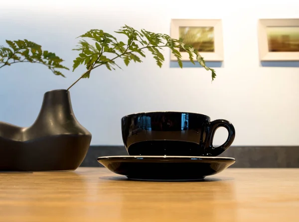 Coffee cup on wood table with fern leaf — Stock Photo, Image