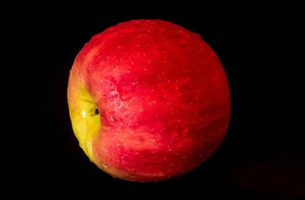 Gouttelette d'eau sur une surface brillante de pomme rouge sur fond noir — Photo