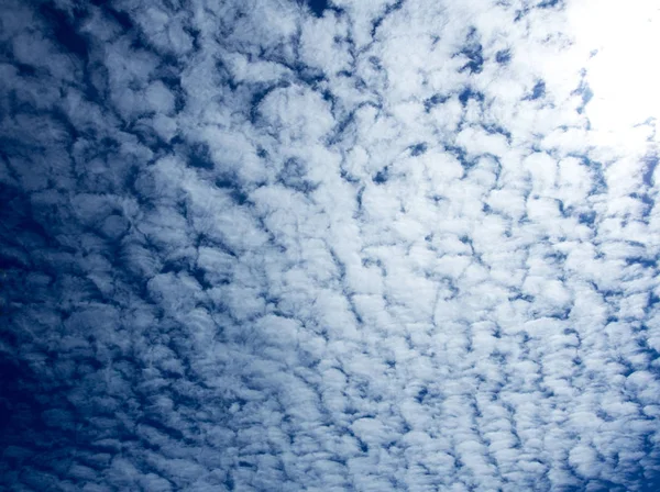 Bílé nadýchané mraky na jasně modré obloze se světlem ze Slunce — Stock fotografie