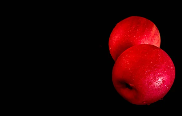 Gouttelette d'eau sur une surface brillante de pomme rouge sur fond noir — Photo