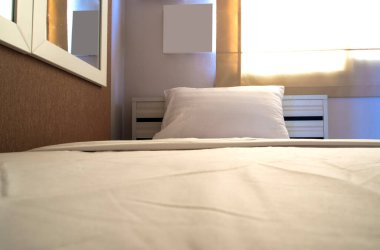 Yatak odasındaki yatakta beyaz battaniye ve yastık.