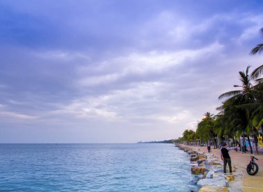 Deniz sakin ve gökyüzü kıyı bölgesinin sabahında yağmur bulutlarıyla kaplanmış.