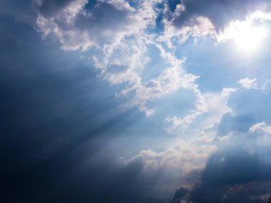 Kırsaldaki kara bulutların arkasındaki güneş ışığı huzmesi.